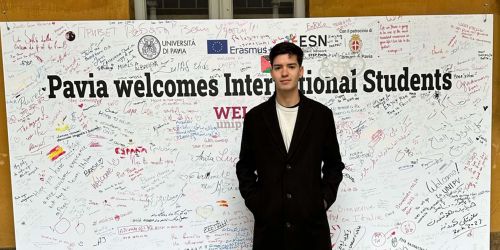 Juan Pablo Fiori davanti al pannello dell'Università di Pavia dedicato all'accoglienza degli studenti internazionali