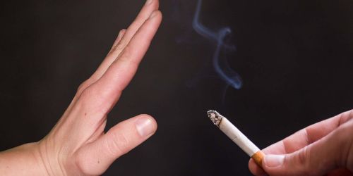 Mano che porge sigaretta e mano tesa come simbolo di "stop"