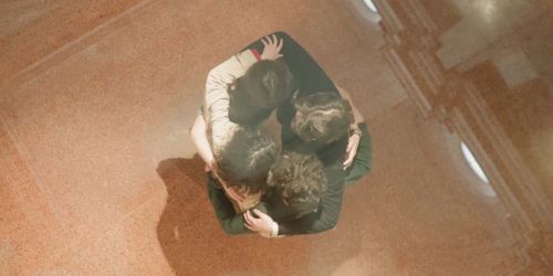 Frame dal video della mostra "L'Epoca fragile?" con ragazzi che si abbracciano visti dall'alto