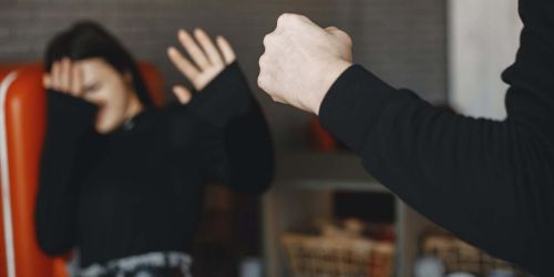 Donna su poltrona che si protegge con le mani da mano chiusa a pugno 