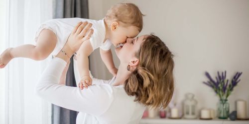 Mamma che tiene in braccio vicino al volto un bambino di pochi mesi