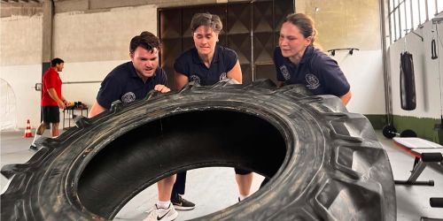 Studenti del Master in Medicina tattica impegnati in esercitazioni fisiche mentre sollevano un grande copertone