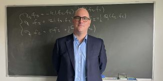 Mattia Zanella, sullo sfondo lavagna con formula matematica