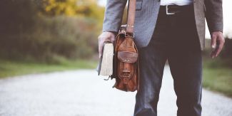 Dettaglio su figura maschile con borsa e libro