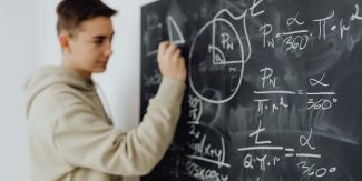 Studente alla lavagna su cui sono scritte formule matematiche