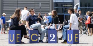 4 studenti seduti su cubi riportanti le iniziali EC2U