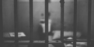 Dettaglio delle sbarre di una cella che si intravede sfuocata sullo sfondo