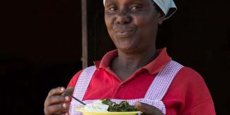 Donna kenyota che tiene in mano un piatto con del cibo