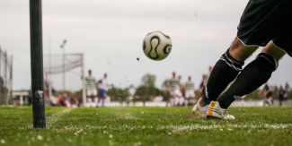 Dettaglio su piedi che calciano pallone durante una partita
