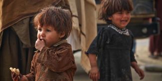 Bambini in situazione di disagio: uno piange e uno mangia un pezzo di pane