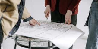 Dettaglio su progetto di architettura con mani di donna e di uomo