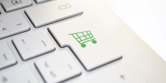 Dettaglio sul tasto "Invio" della tastiera di un computer su cui è disegnato il simbolo di un carrello della spesa
