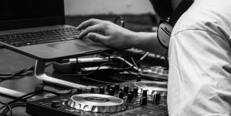 Dj con cuffie davanti alla consolle e al pc