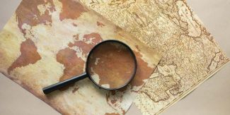 Due carte geografiche antiche su cui è appoggiata una lente di ingrandimento