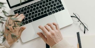 Mani che digitano su pc portatile posto su scrivania