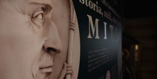 Dettaglio di uno dei pannelli della mostra "Alle origini dell'Università di Pavia: storia, miti, storia dei miti". In primo piano parte del medaglione raffigurante Lotario posto a lato dell'ingresso principale del Palazzo Centrale dell'Università di Pavia.