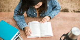 Ragazza che legge seduta a un tavolo di pietra