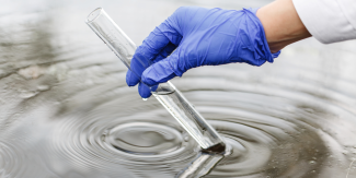 Mano che raccoglie con una provetta campione d'acqua