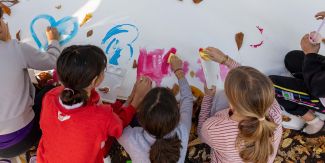 Alcuni dei bambini e delle bambine che hanno preso parte al progetto mentre disegnano sul grande telo
