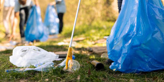 Dettaglio di pinza raccogli rifiuti che raccoglie immondizia abbandonata