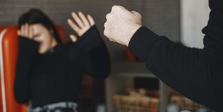 Donna su poltrona che si protegge con le mani da mano chiusa a pugno 