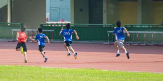 Bambini di spalle che corrono su pista di atletica