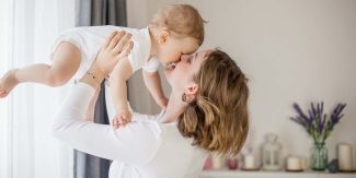 Mamma che tiene in braccio vicino al volto un bambino di pochi mesi