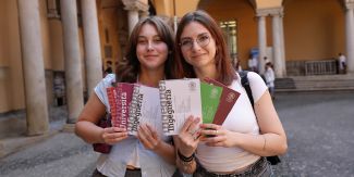 Due studentesse nei cortili del Palazzo Centrale UniPv che tengono in mano le brochure dei diversi corsi di studio