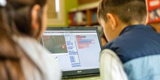 Un bambino e una bambina di fronte al pc, impegnati in un laboratorio CoderDojo
