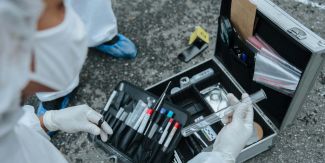 Tecnico della scientifica sulla scena del crimine con valigetta, provette, buste raccogli campioni, ecc.