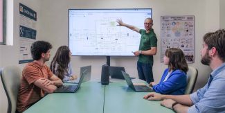 Enea Parimbelli illustra alcuni grafici su un maxi schermo ai ricercatori del Laboratorio di Informatica Biomedica “Mario Stefanelli” UniPv