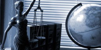 Statua della giustizia affiancata a un mappamondo su una scrivania