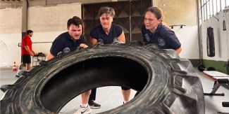 Studenti del Master in Medicina tattica impegnati in esercitazioni fisiche mentre sollevano un grande copertone