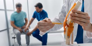 Trattamento per lesioni al ginocchio. Uomo adulto con lesione al ginocchio durante una visita con il medico traumatologo presso una clinica medica.