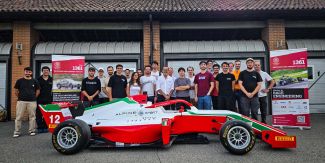 Foto di gruppo di alcuni dei partecipanti al Master con un'auto da corsa