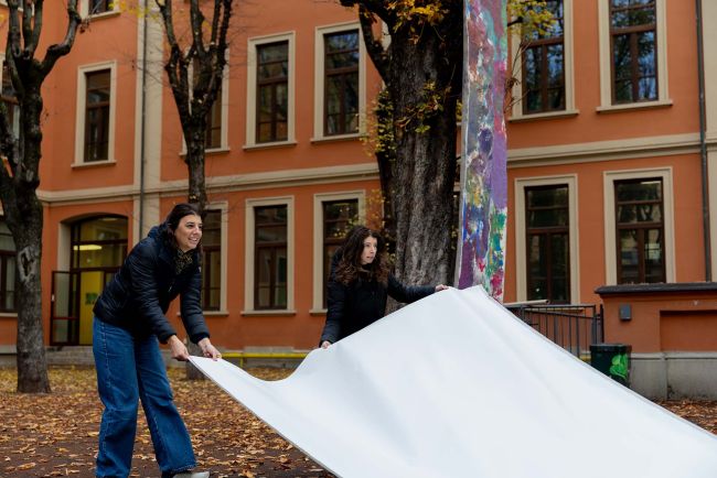 Le ricercatrici predispongono il telo su cui disegneranno bambini e bambine.